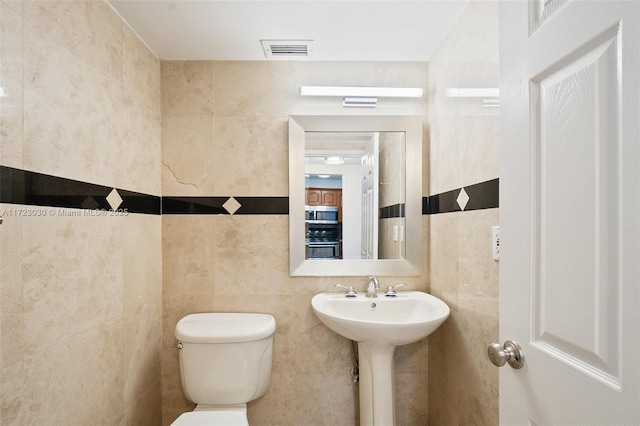 bathroom featuring sink, tile walls, and toilet