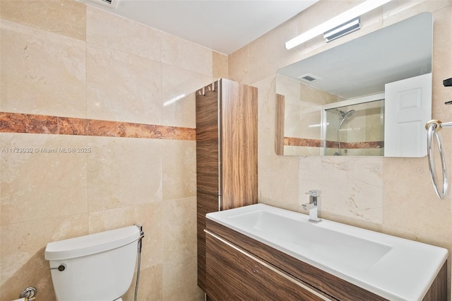 bathroom featuring tile walls, vanity, a shower with shower door, and toilet