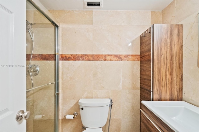 bathroom featuring walk in shower, vanity, toilet, and tile walls