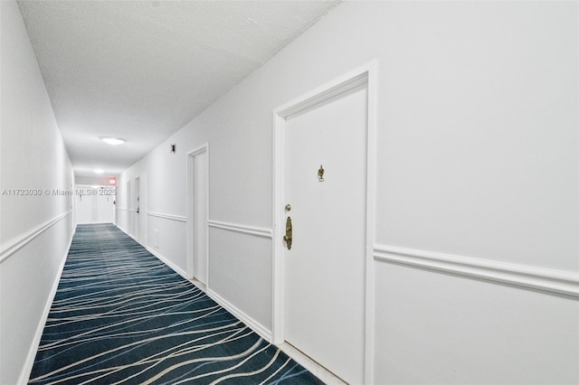 hall featuring carpet floors and a textured ceiling