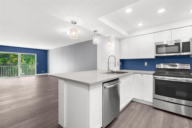 kitchen featuring kitchen peninsula, white cabinetry, sink, and appliances with stainless steel finishes