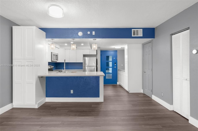 kitchen with sink, hanging light fixtures, dark hardwood / wood-style floors, appliances with stainless steel finishes, and white cabinetry