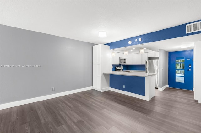 kitchen with sink, kitchen peninsula, decorative light fixtures, white cabinets, and appliances with stainless steel finishes