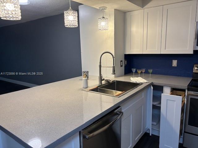 kitchen featuring pendant lighting, sink, white cabinetry, kitchen peninsula, and stainless steel appliances