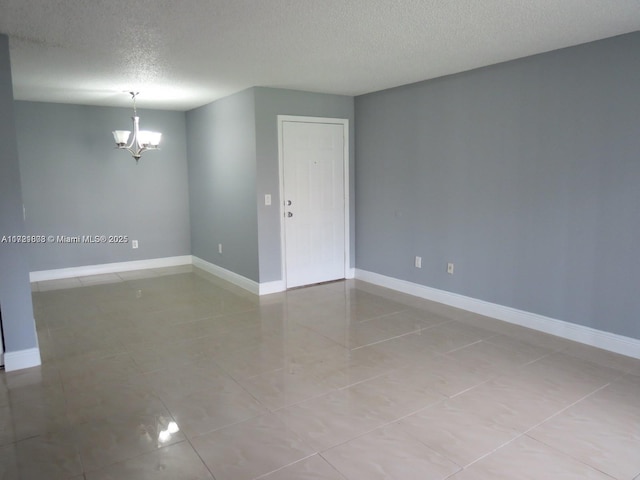 spare room featuring light tile patterned floors, a textured ceiling, and a chandelier