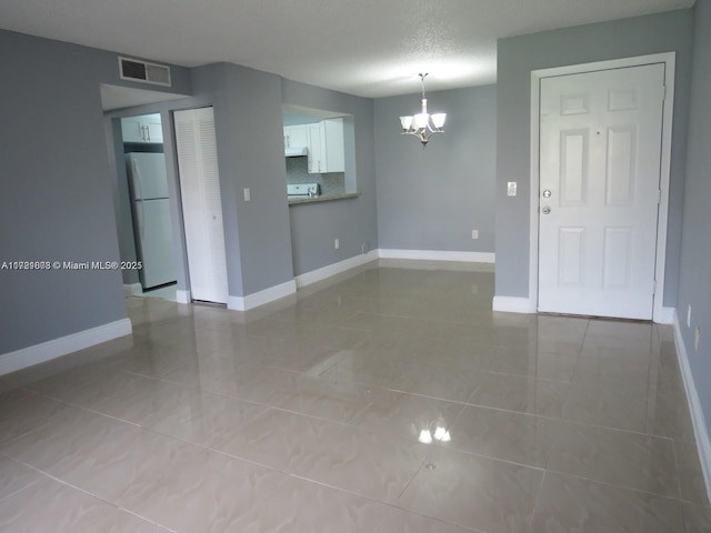 unfurnished room featuring light tile patterned flooring, a textured ceiling, and a notable chandelier