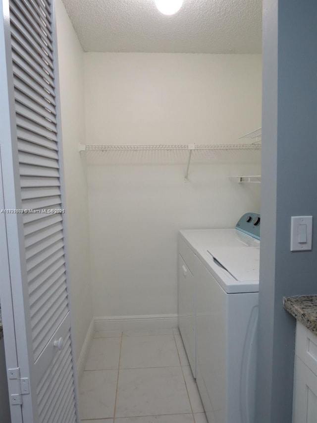 clothes washing area with light tile patterned floors, a textured ceiling, and separate washer and dryer