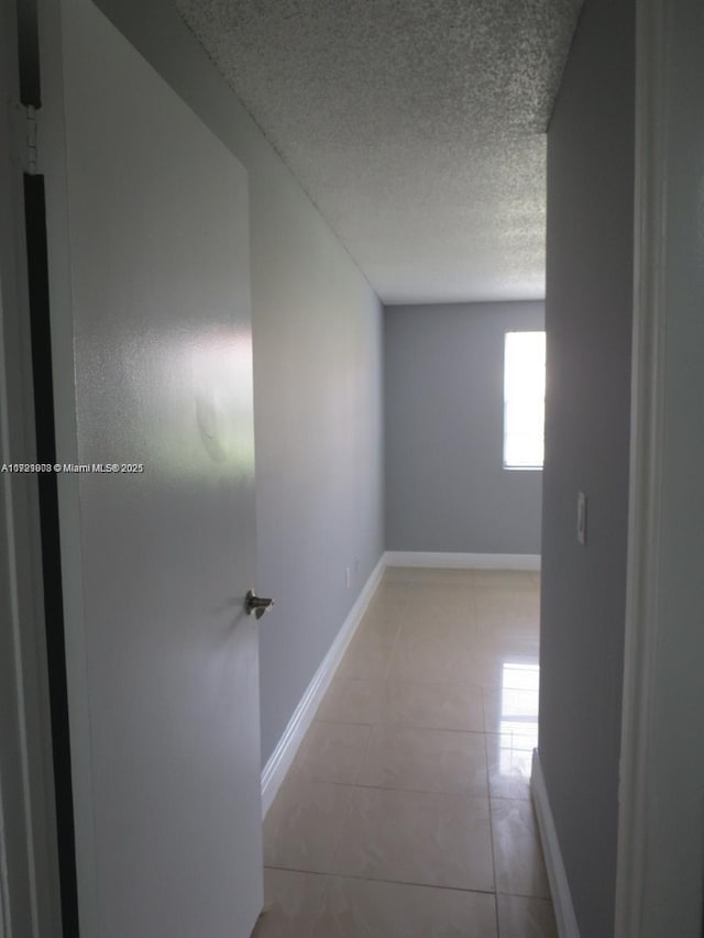 hallway with light tile patterned flooring and a textured ceiling