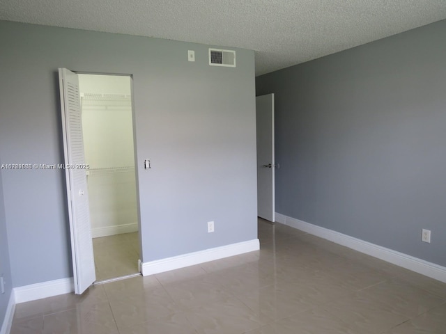 unfurnished bedroom with light tile patterned floors, a textured ceiling, and a closet