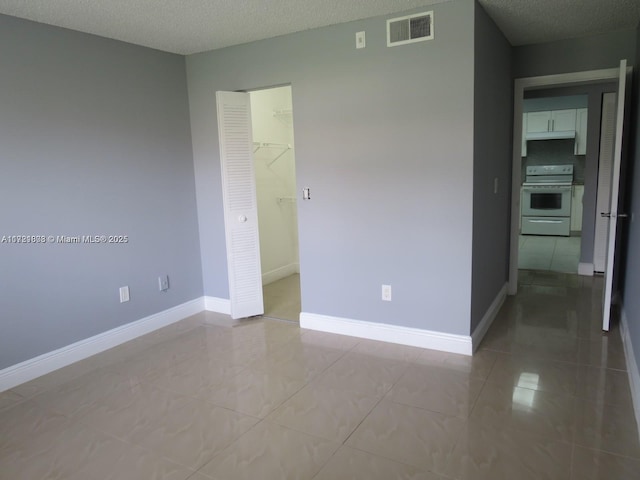 tiled empty room with a textured ceiling