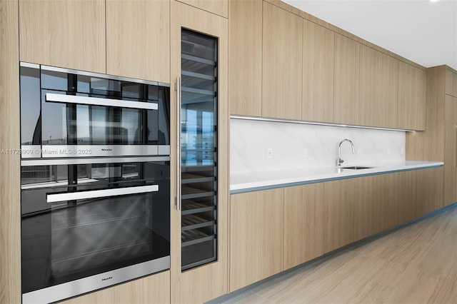 kitchen featuring sink, wine cooler, light hardwood / wood-style flooring, double oven, and light brown cabinetry