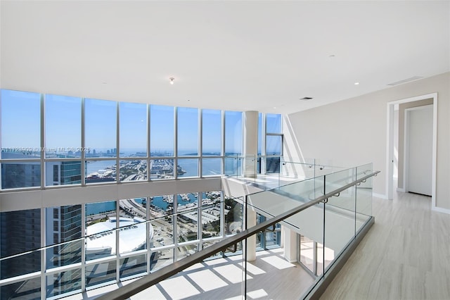 corridor with a water view and light hardwood / wood-style floors