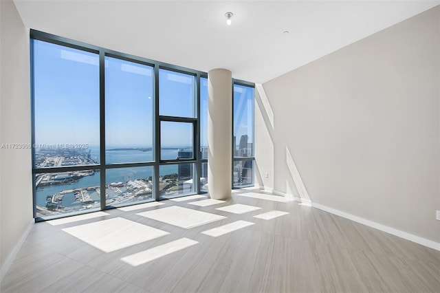 spare room featuring a water view and expansive windows