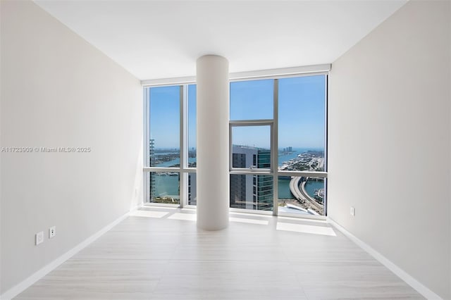 unfurnished room featuring floor to ceiling windows, a wealth of natural light, and a water view