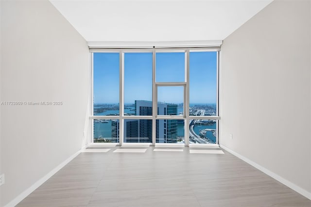 unfurnished room with floor to ceiling windows and a water view