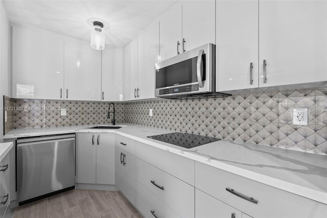 kitchen with light stone counters, decorative backsplash, white cabinetry, appliances with stainless steel finishes, and sink