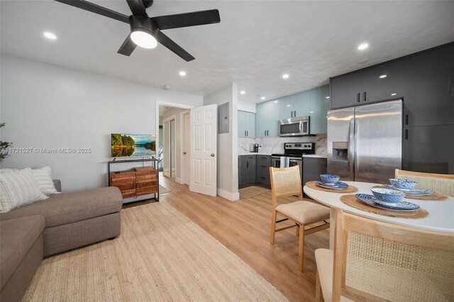 kitchen with light hardwood / wood-style flooring, stainless steel appliances, backsplash, blue cabinets, and ceiling fan