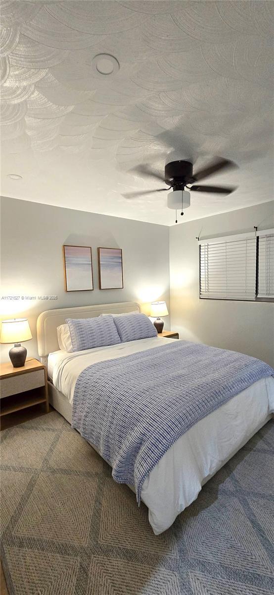 bedroom with ceiling fan, carpet floors, and a textured ceiling