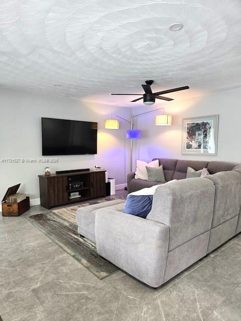 living room featuring ceiling fan and a textured ceiling