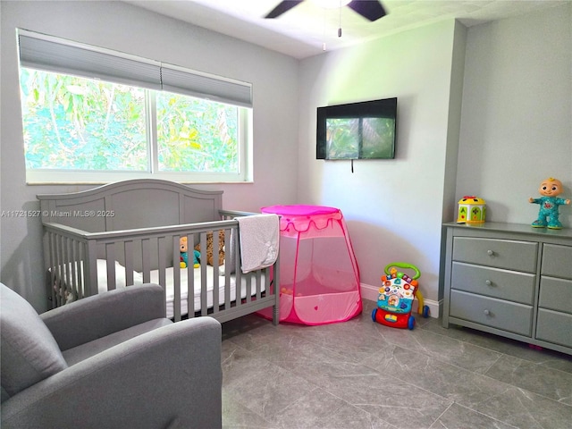 bedroom with ceiling fan and a nursery area