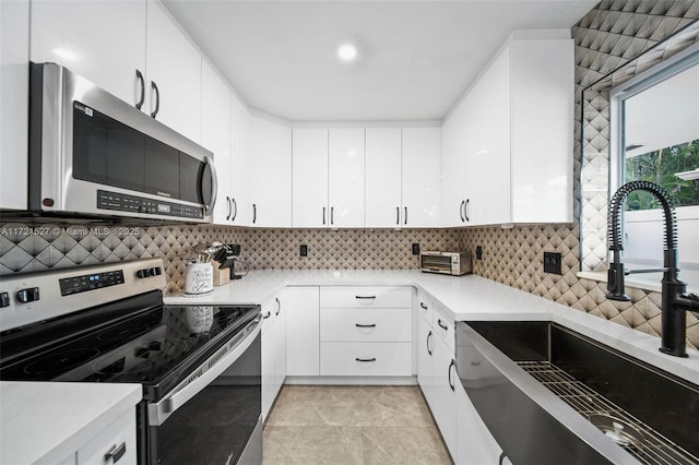 kitchen featuring appliances with stainless steel finishes, sink, white cabinetry, and backsplash