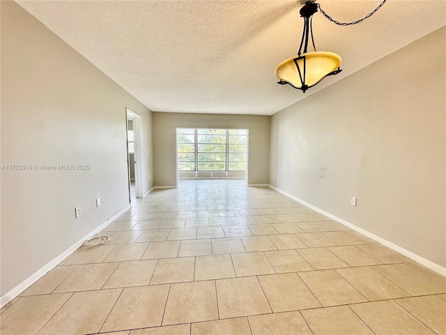 tiled empty room featuring a textured ceiling