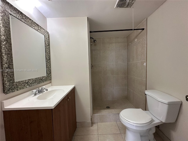 bathroom with tile patterned floors, vanity, toilet, and tiled shower