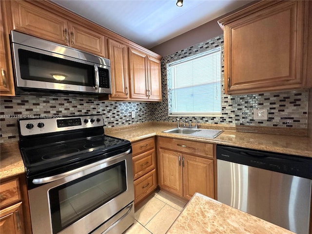 kitchen with appliances with stainless steel finishes, backsplash, light tile patterned floors, and sink