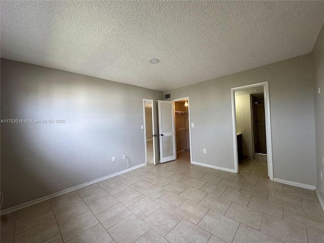 unfurnished bedroom with a textured ceiling, a walk in closet, and a closet