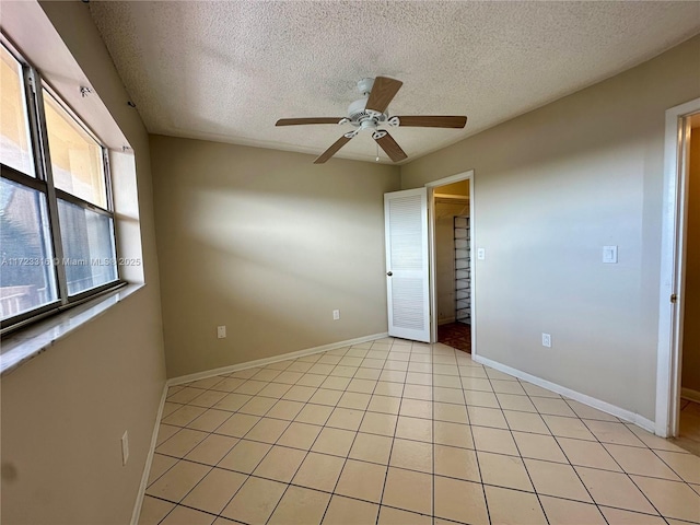 unfurnished room featuring ceiling fan, light tile patterned floors, and a textured ceiling