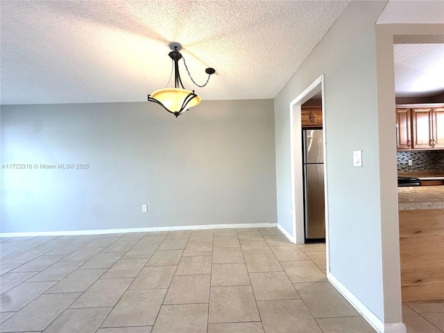 tiled empty room featuring a textured ceiling