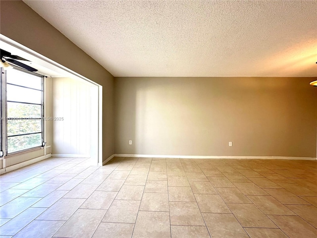 unfurnished room featuring ceiling fan, light tile patterned flooring, and a textured ceiling