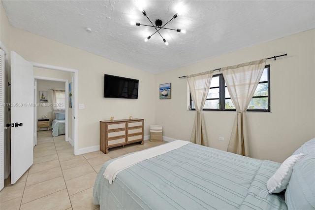 bedroom featuring a notable chandelier, light tile patterned floors, and a textured ceiling