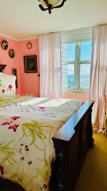 bedroom with ceiling fan, ornamental molding, and carpet floors