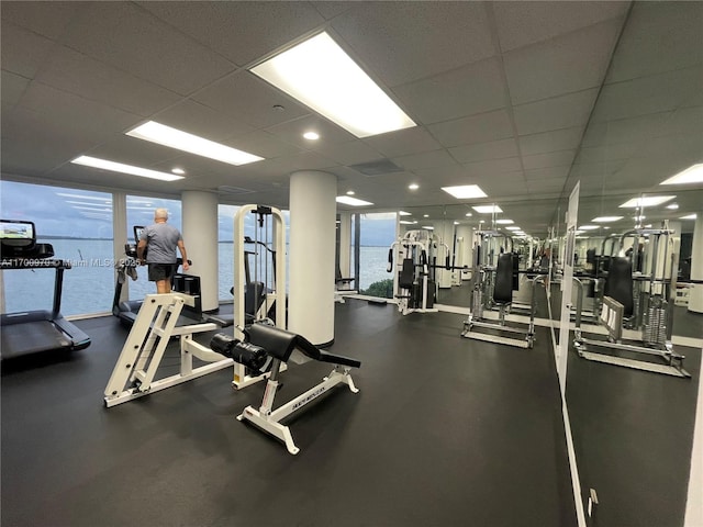 gym featuring a drop ceiling, expansive windows, and a water view