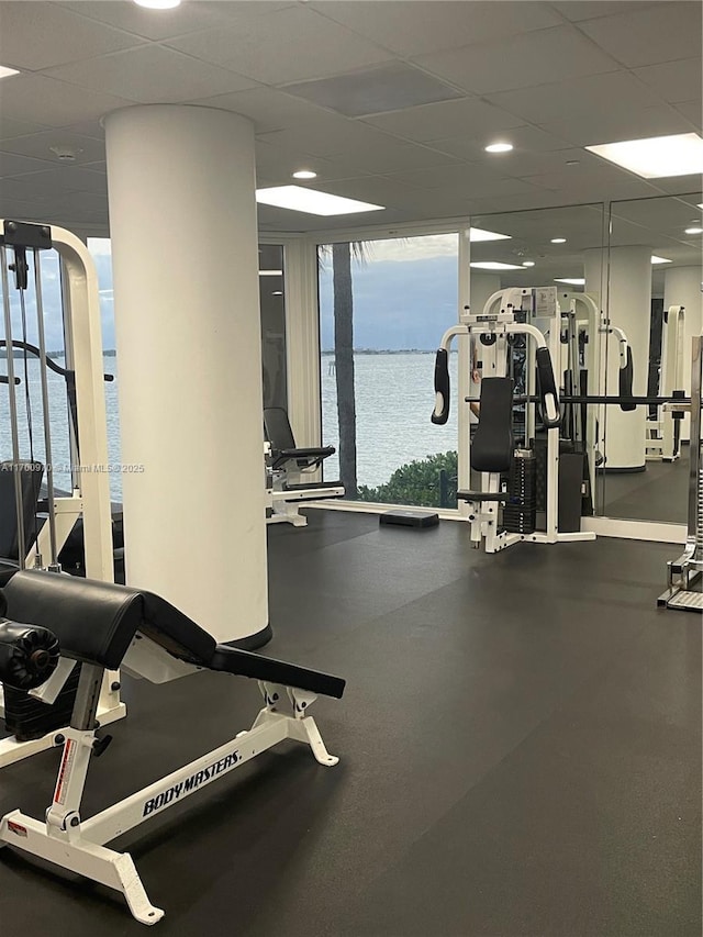 exercise room featuring a drop ceiling and a water view