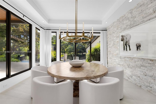 tiled dining area with an inviting chandelier and a raised ceiling