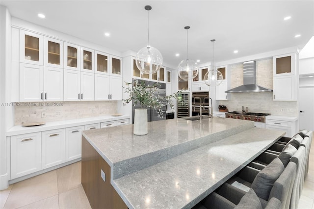 kitchen featuring white cabinetry, a spacious island, and wall chimney range hood