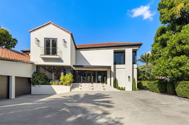 mediterranean / spanish-style home featuring a garage and a balcony