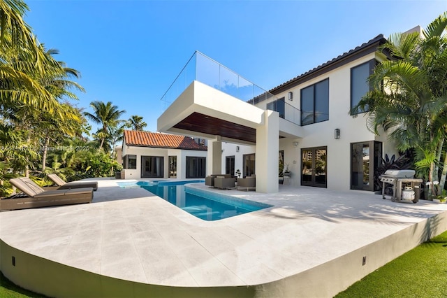 rear view of property featuring outdoor lounge area, a balcony, and a patio