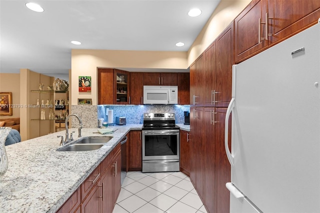 kitchen featuring sink, light tile patterned floors, tasteful backsplash, light stone counters, and stainless steel appliances