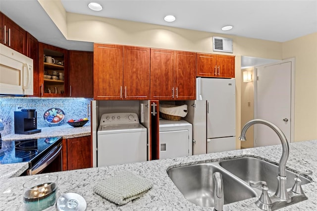 kitchen with light stone counters, white appliances, sink, and washer / clothes dryer