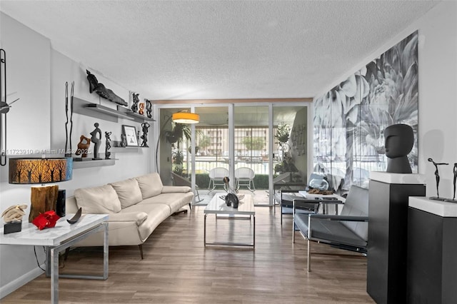 living room featuring wood-type flooring, a textured ceiling, and a wall of windows