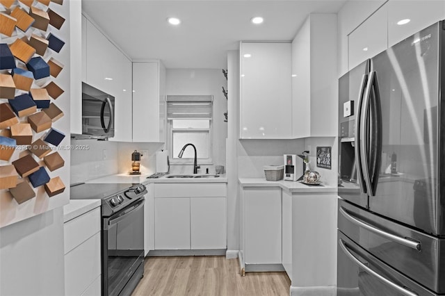 kitchen with sink, stainless steel refrigerator with ice dispenser, black / electric stove, refrigerator, and white cabinets