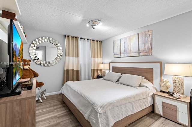 bedroom featuring light hardwood / wood-style floors and a textured ceiling