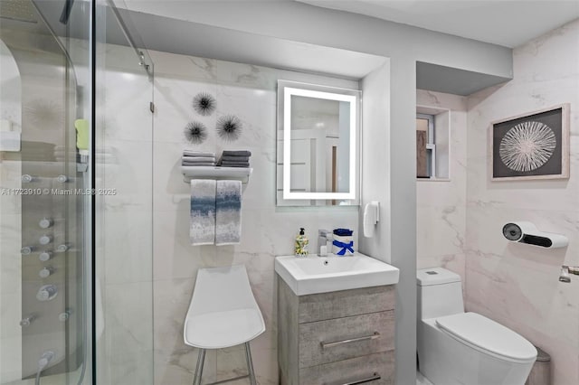 bathroom featuring walk in shower, vanity, toilet, and tile walls