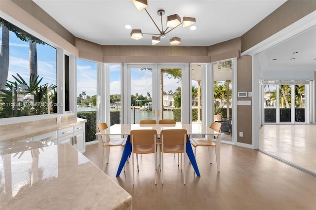 sunroom with a notable chandelier and a water view