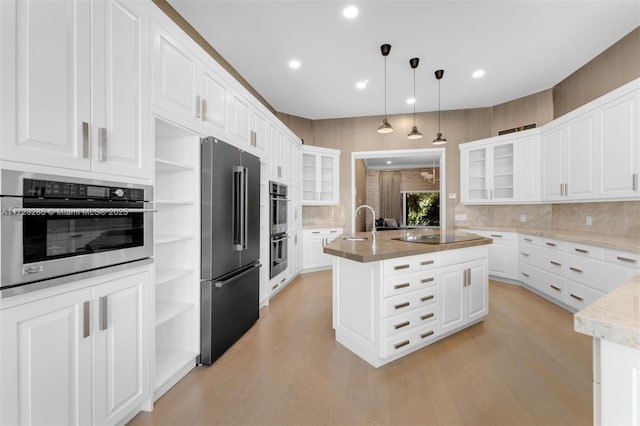 kitchen with white cabinets, appliances with stainless steel finishes, and an island with sink