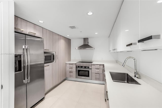 kitchen featuring wall chimney range hood, sink, and appliances with stainless steel finishes