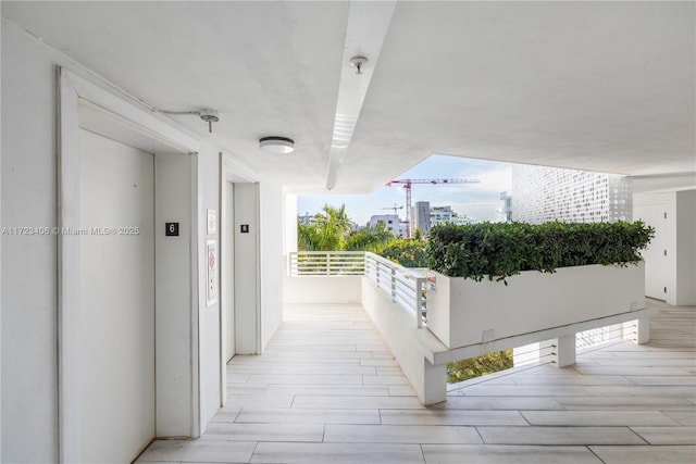 corridor featuring elevator, a wealth of natural light, and light hardwood / wood-style floors